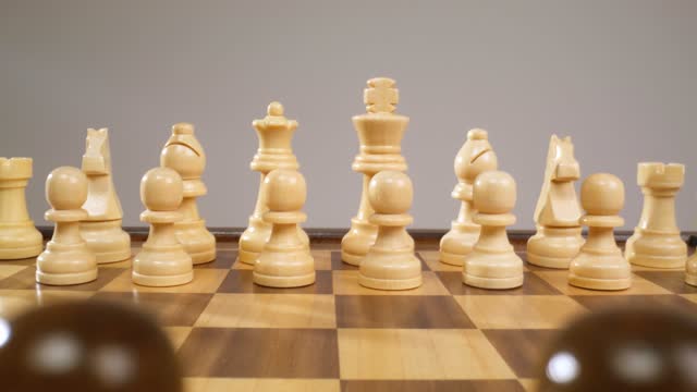 The camera zooms out on a chessboard surface gliding along the chess pieces.