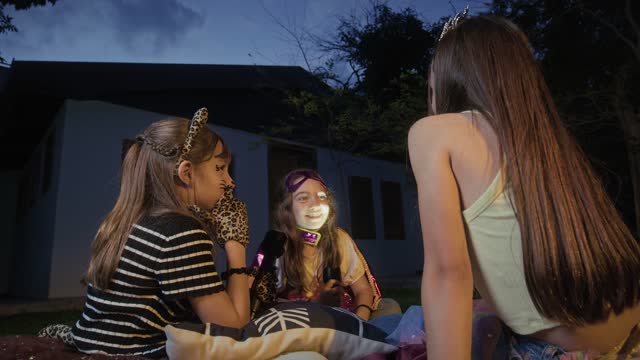 Girls gather in the backyard for stories at dusk.