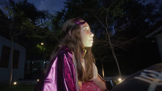 Girl in a purple cape rides outdoors under night sky.