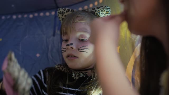 Child in leopard costume plays in tent with light.