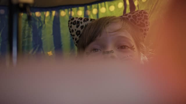 Child in leopard costume smiles with painted face.