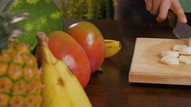 Person cutting banana for a fruit cocktail.