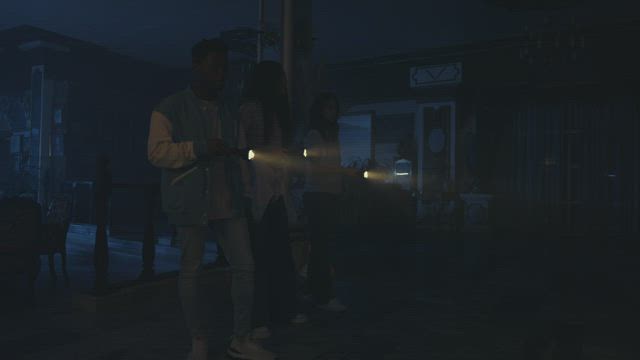 Three young people exploring a haunted house at night.