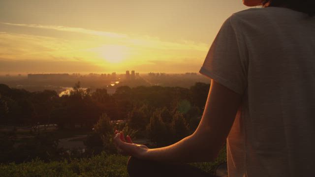 Girl meditating in yoga pose at sunset.