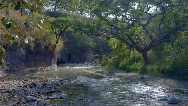 Flying over a relaxing creek full of rock on the countryside.