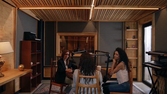 Women recording a podcast at a record studio .