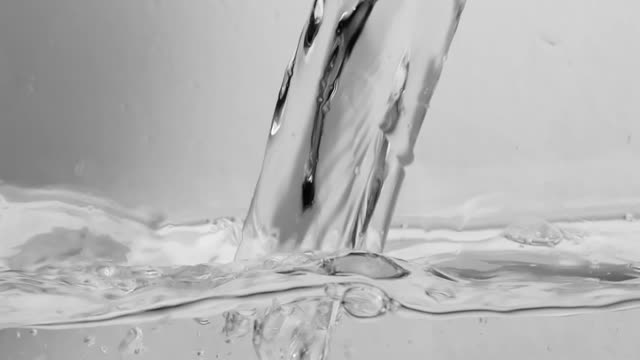 Close up of a trnasparent stream of water filling a container .