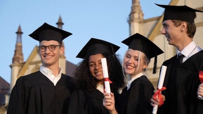 Graduating students smiling and laughing with diplomas..