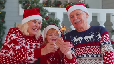 Happy Senior Couple Grandparents with Granddaughter Holding Lit Bengal Christmas Lights Sparklers.