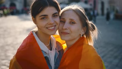 Portrait of a Lesbian Couple Wrapped in the Lgbt Flag Looking at the Camera.