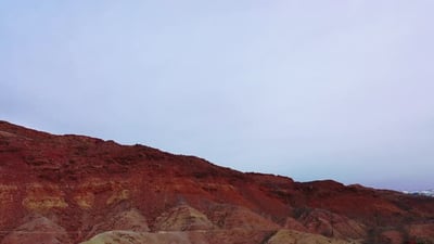 Overtake shot of orange and arid mountains - aerial view.