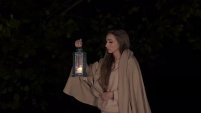 Scary Young Girl with a Lit Candle Lantern in Night Forest.