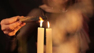 a Girl Lights a Palo Santo Stick on a Lit Candle Close Up and Mystery.